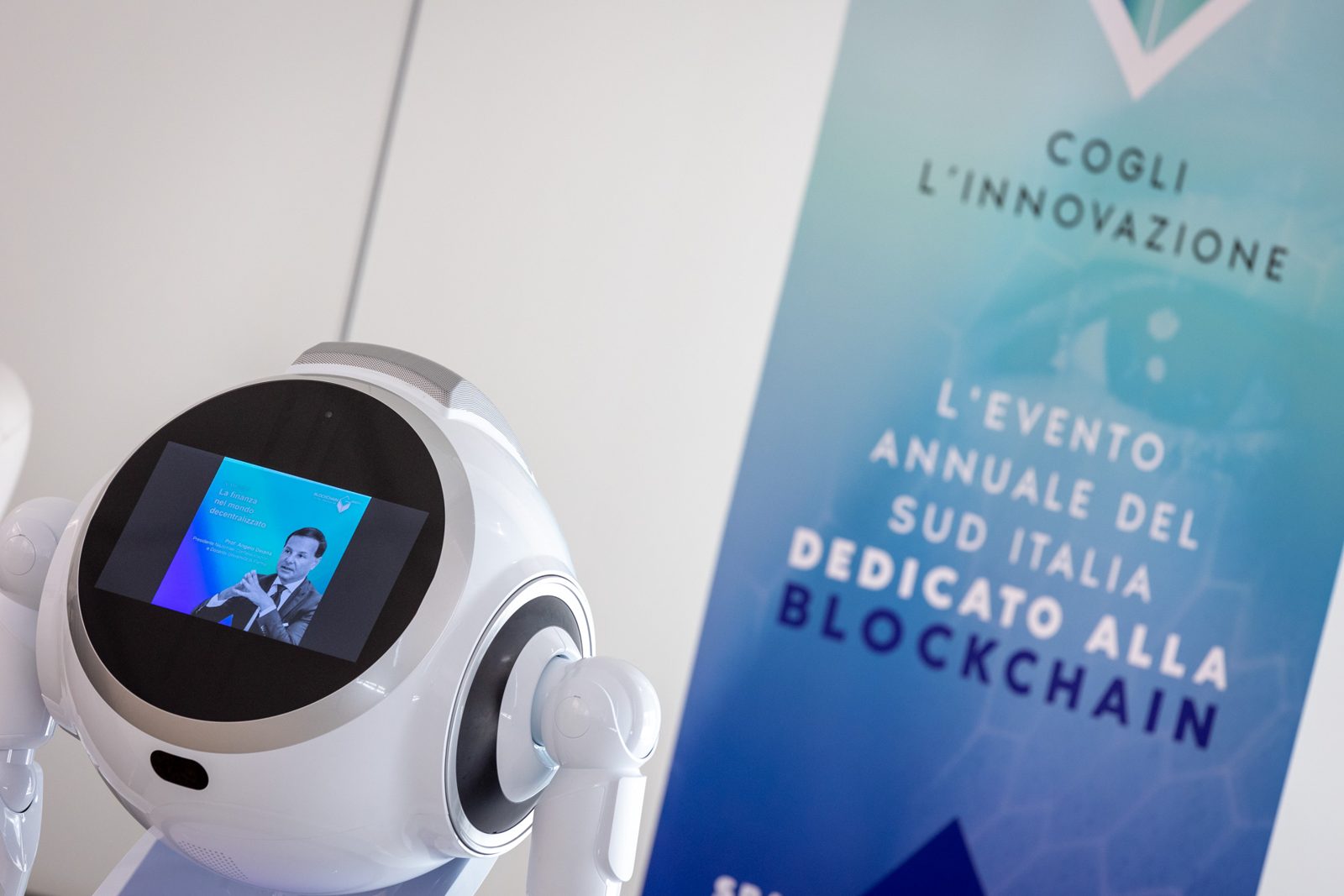 Il robot accoglie i partecipanti accanto al roll-up dell'evento